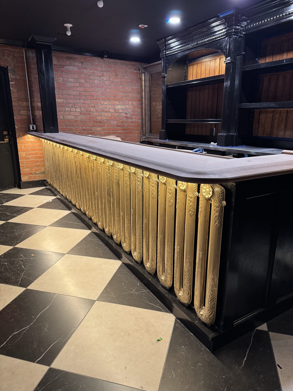 Finished bar with ornate gold fluted columns and checkered marble floor