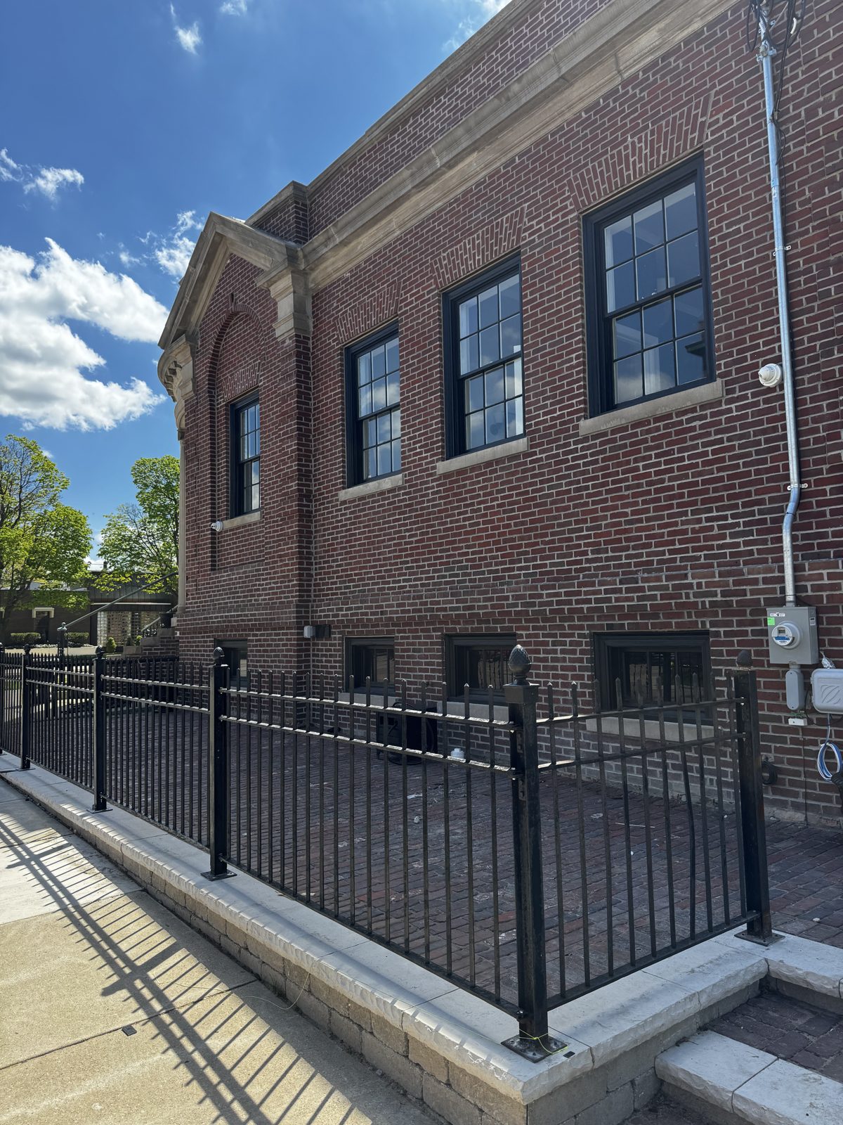 Restored outdoor patio with brick wall and wrought iron fence